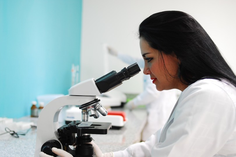 woman seated looking through microscope