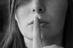 woman with finger to mouth signalling 'shhh'