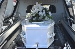 white casket in hearse with flowers