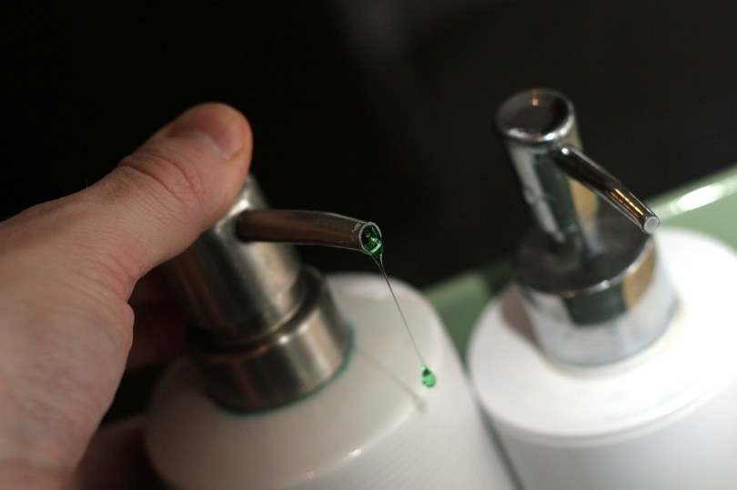 hand pressing one of two white liquid soap pumps