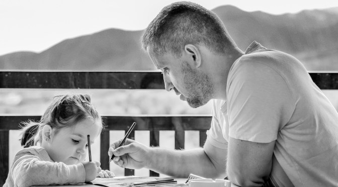 father teaching girl with pens and paper