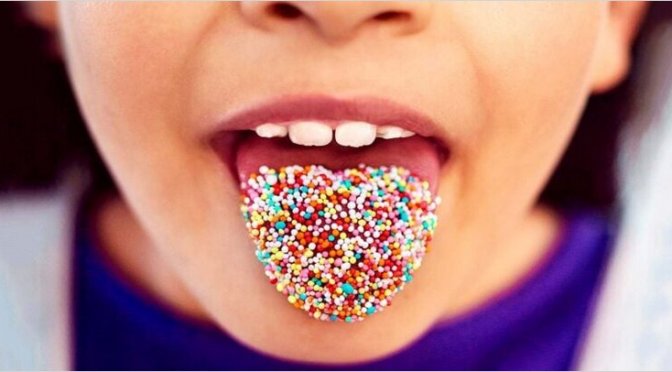 child with coloured candy on tongue