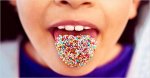child with coloured candy on tongue
